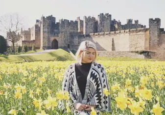 woman in field of flowers near castle