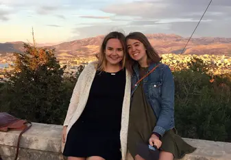 two females sitting on stone wall