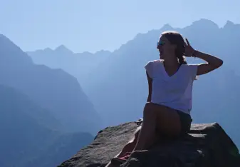 woman sitting on rock in mountains