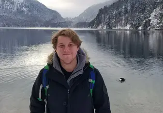 male at lake with snowy mountains