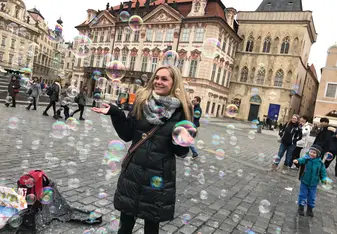 girl standing in the middle of Old Town Square surrounded by bubbles
