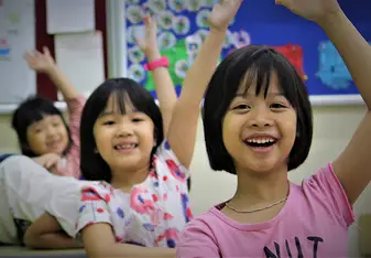 An image of Vietnamese students raising their hands in a classroom.
