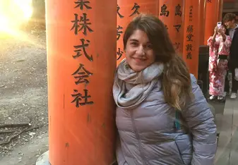 Girl leaning on a column with Japanese carvings.