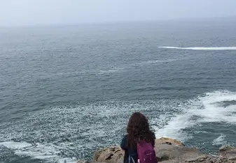 Woman sits by the coast.