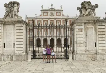 3 girls taking picture on a gate of a huge house