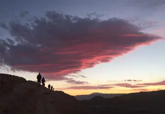 Hikers on a hill in the Atacama desert with sunset in background
