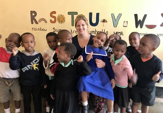 woman having her picture taken along with group of school kids