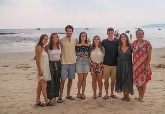 group of men and women having their picture taken on a beach seashore