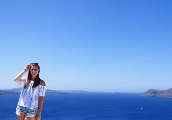 a lady having her picture taken with the blue sea as her background