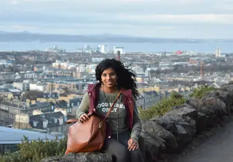 the girl is sitting on the rock smiling