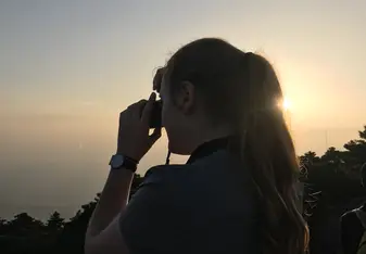 silhouette of a woman taking a picture of the sunset view
