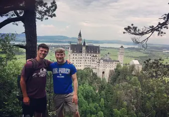 Two guys posing at a place overlooking a castle.