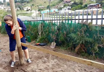 A lady holds a wooden post.