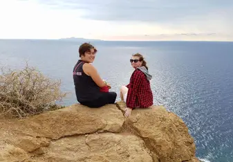 Two women sitting at a cliff.