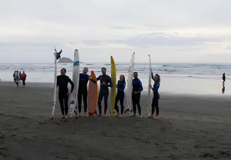 Group of people holding surfboards at the beach.