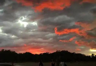 People walking under the sunset skies.