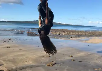 A lady hangs by a rope upside down.