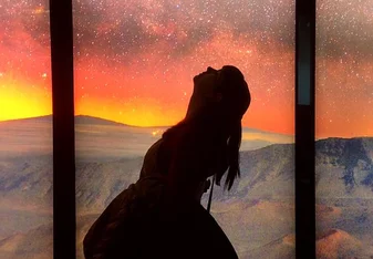 A lady bends backward and gazes t he beautiful sky.
