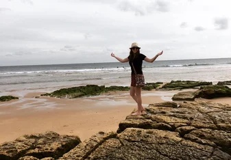 A lady stands near the coast.