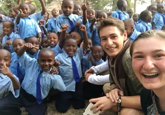 Two volunteers pose with schoolchildren .