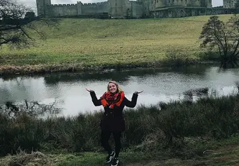 A lady poses near a castle.