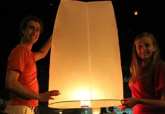 a young man and woman flying a sky lantern