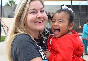 a young lady carrying and cuddling a little girl