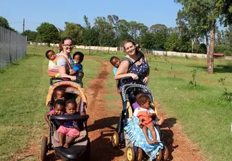 two woman carrying and strolling little boys and girls