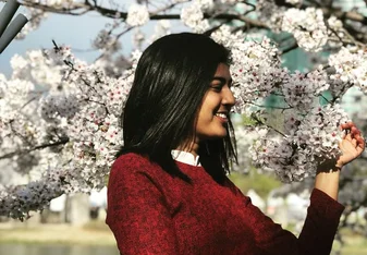 a young woman looking at a beautiful tree full of blooming flowers