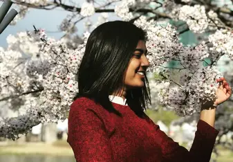 a young woman looking at a beautiful tree full of blooming flowers