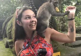 a woman holding a small monkey on her shoulder