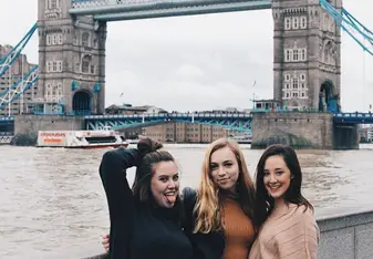 Three women posing for a photo near the Tower Bridge.