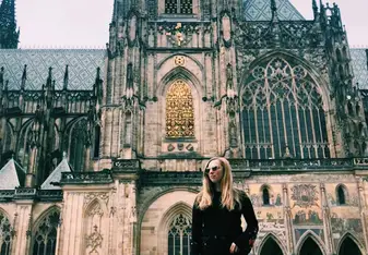 A woman poses near a Cathedral.