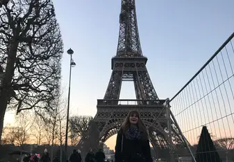A woman poses for a photo at the Eiffel Tower.
