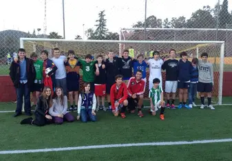 Group of people posing for a photo at a soccer field.