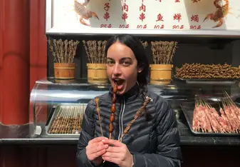 A woman holds sticks of street food.