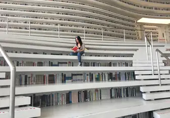A woman reads a book inside a huge library.