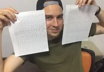 A guy shows two sheets of papers with Chinese writings.