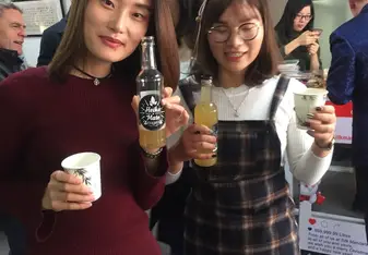 Two Chinese each holding a drink.