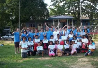 Children and volunteers pose for a photo at an open field.