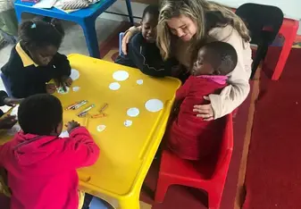 A woman hugs two children inside a classroom.