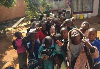 A woman is happily surrounded by children.