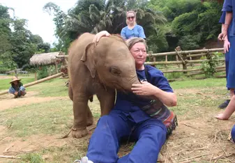 A woman hugs a young elephant.