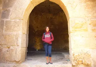 A lady stands under an arch.