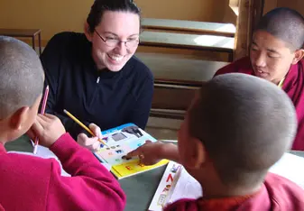 Volunteer in Nepal looking at book with student