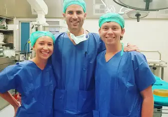 Three persons in scrub suit inside an operating room.