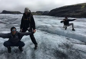 Three persons doing fun poses on ice.
