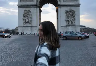 A woman poses near the Arc de Triomphe