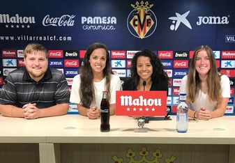 Marketing interns sit at a table with logos behind them