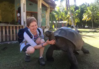 A woman touching a huge turtle.